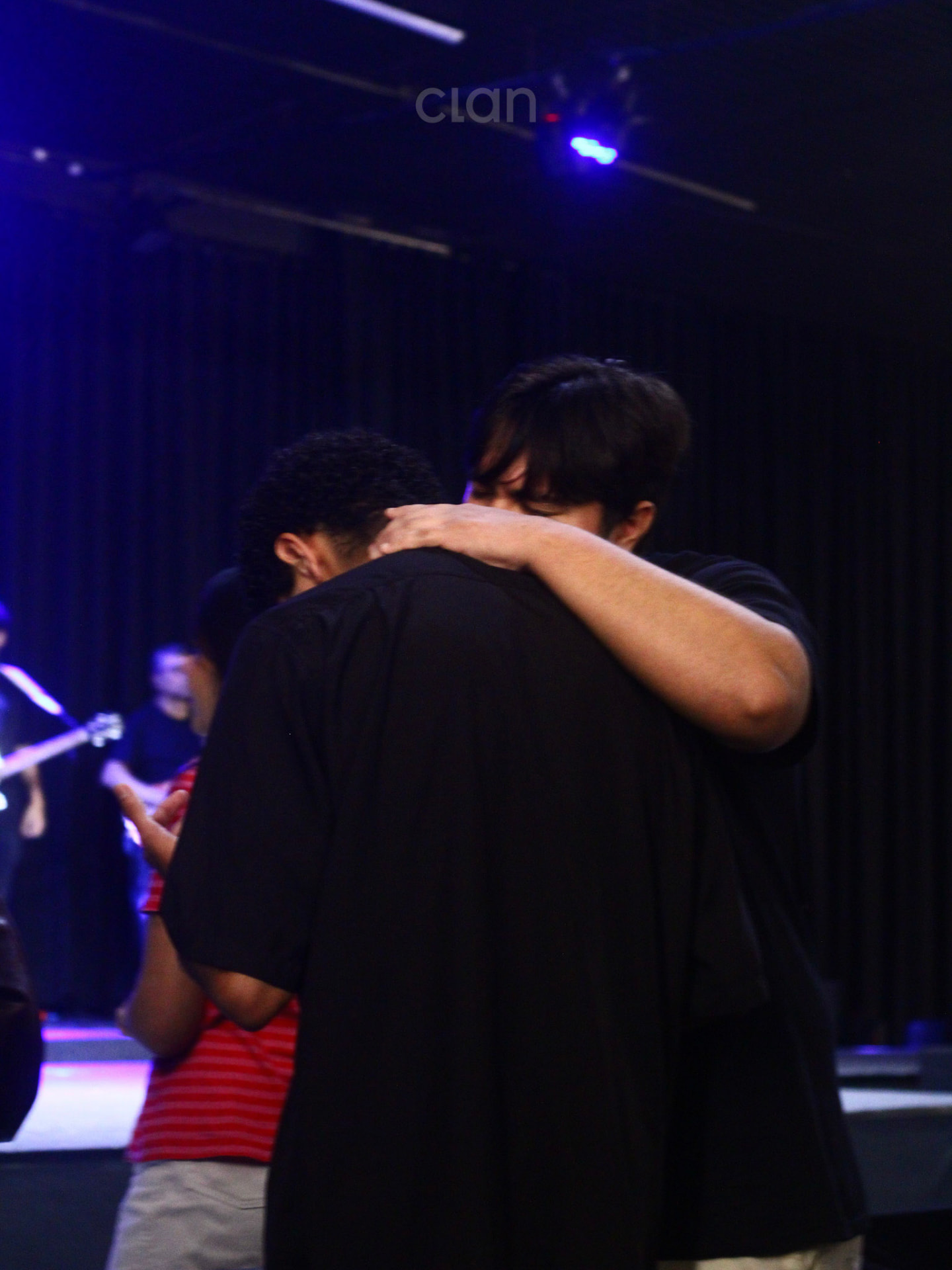Jovens orando abraçados no culto CLAN